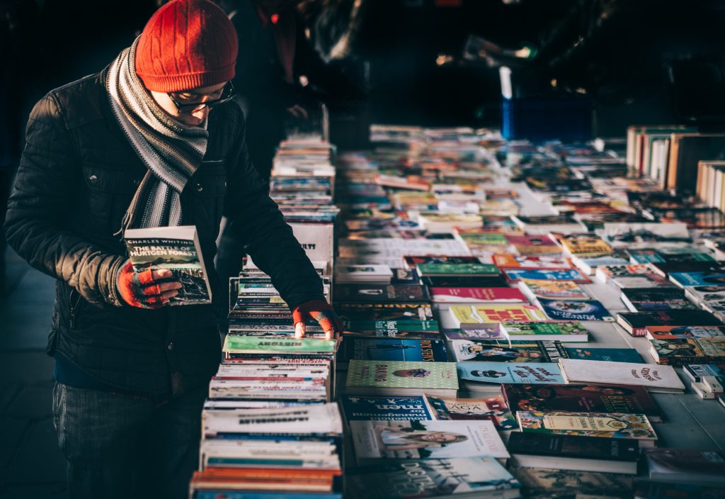 man-looking-at-books-outside-fall-season